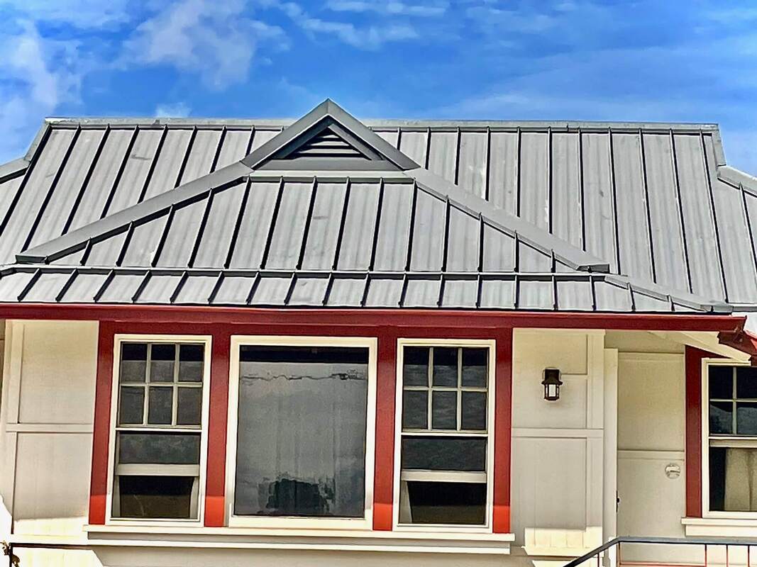 White wooden house with red trim and metal roof